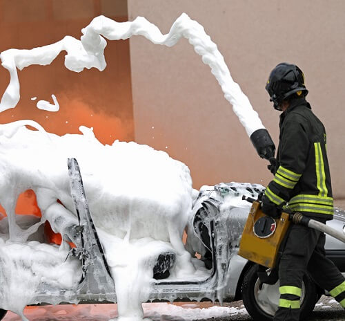 firefighter using aqueous film forming foam to put out a fuel fire