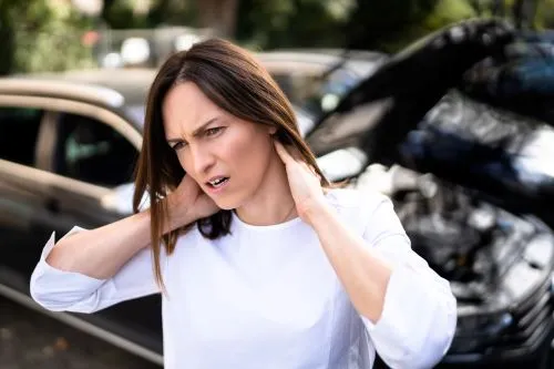 A woman rubs her neck due to whiplash after a car accident.