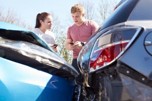 A man and a woman exchange insurance information after a car accident.