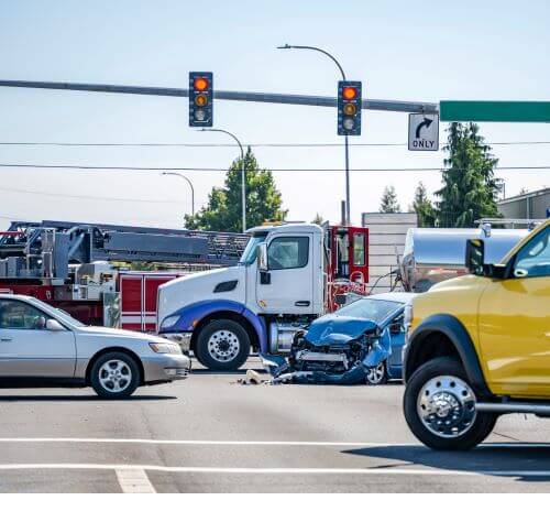 Cars are stopped in an intersection after a truck accident with a small blue car.