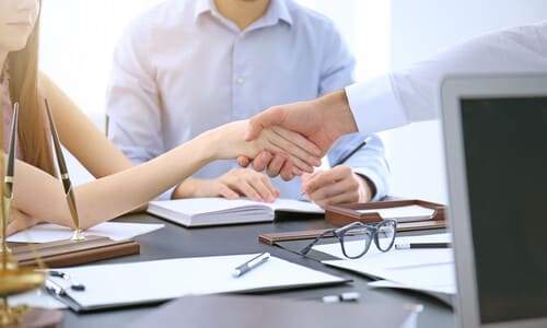 A couple shaking hands with a personal injury lawyer after agreeing to work together.