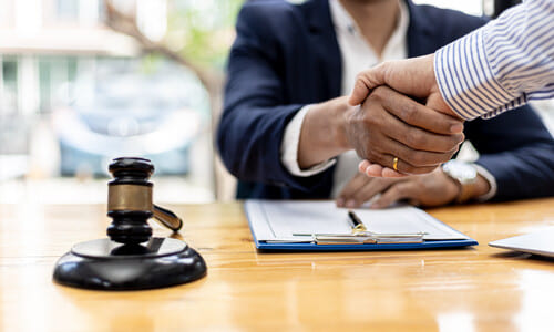 A client meeting with a personal injury lawyer and shaking hands before a case consultation.