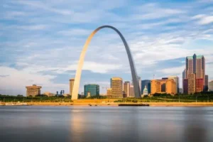 A panoramic view of the St. Louis arch in Missouri against a city  backdrop.